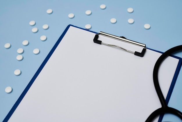 A clipboard with blank paper medical pills and stethoscope