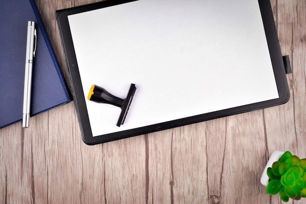 Clipboard with blank paper and office stationery on wooden table