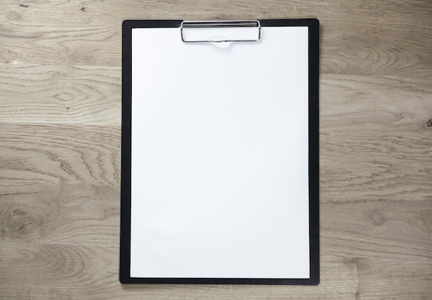 Clipboard with blank sheet on wooden background