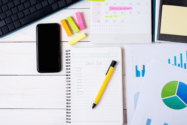 Clipboard with check list on notebook with pen and smartphone and document with keyboard computer, calendar have plan on memo. Top view, Flat lay image.