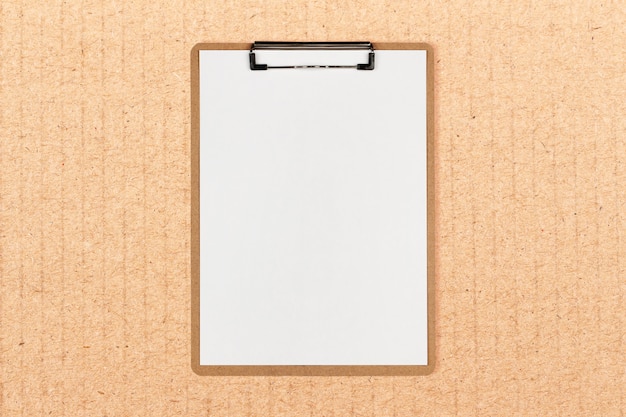 Clipboard with white sheet and space for text on craft paper background