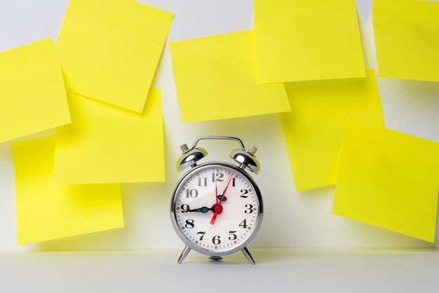 A clock along with yellow sticky notes to include goals reminders important dates or birthdays