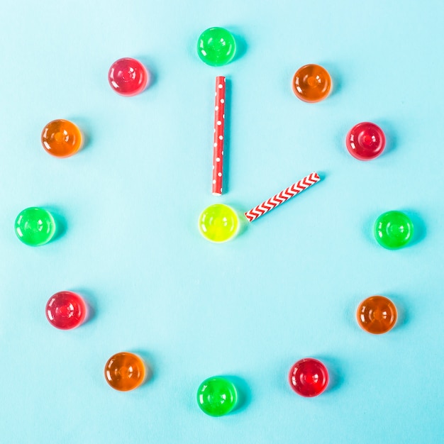 Clock lined with colorful candies on a blue background