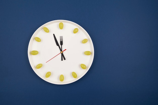 Clock made of grapes on blue