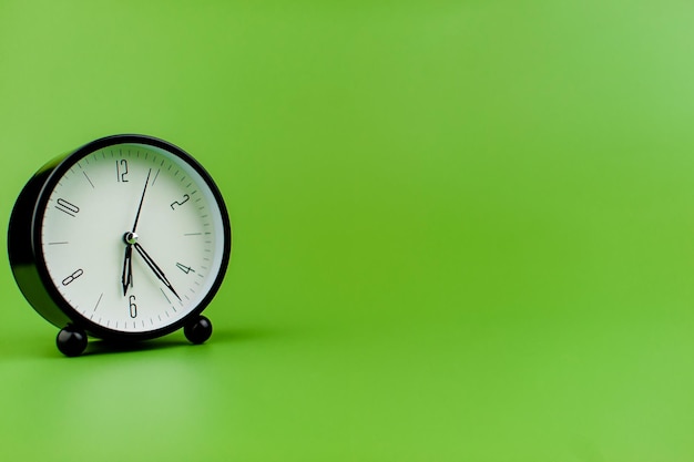 Clock precious time alarm clock on green background concept of time working with time