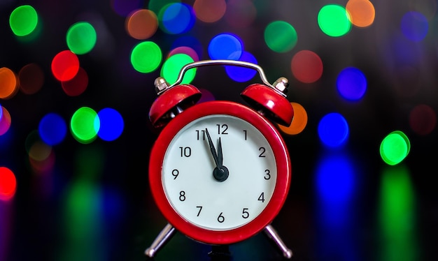 The clock with hands shows five minutes to midnight against the background of colored lights. Bokeh