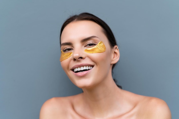 Close beauty portrait of a topless woman with perfect skin and natural makeup shiny patches under the eyes to moisturize the skin and relieve puffiness of the face