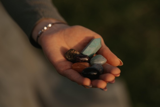 A close photo of a bunch of stones on the hand of a woman for magical therapy