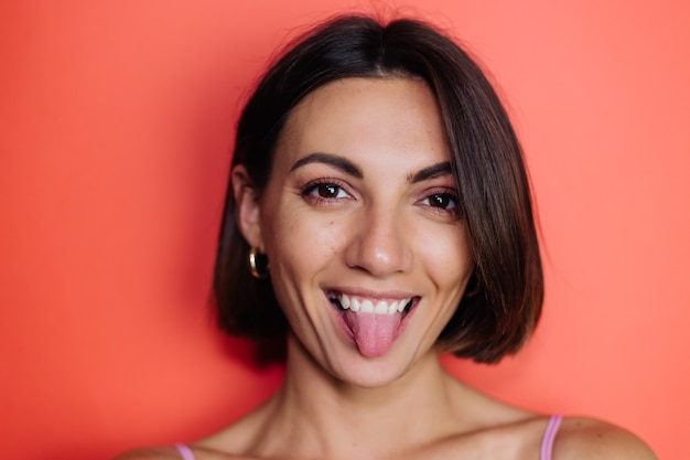 Close portrait of woman on red wall playful shows tongue