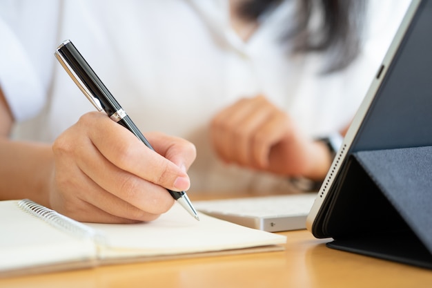 Close shot of businesswoman hands holding a pen writing something