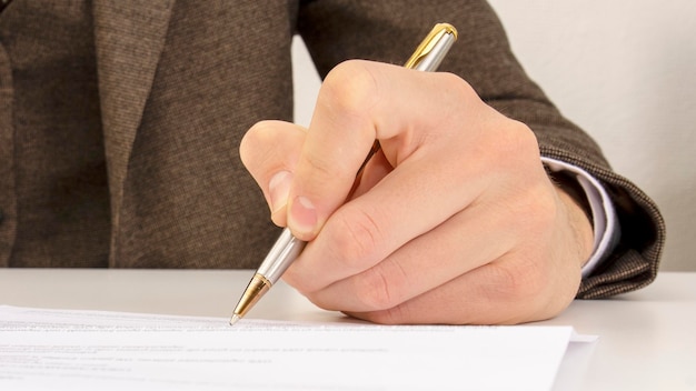 Close shot of a human hand writing something on the paper on the foreground business concept