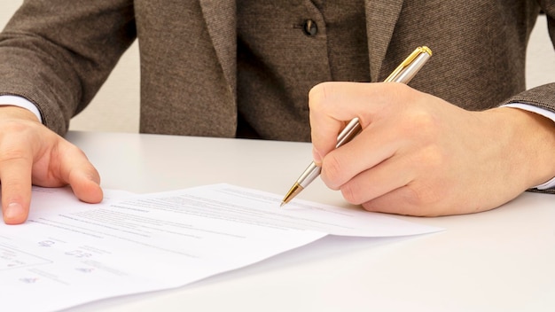 Close shot of a human hand writing something on the paper on the foreground business concept