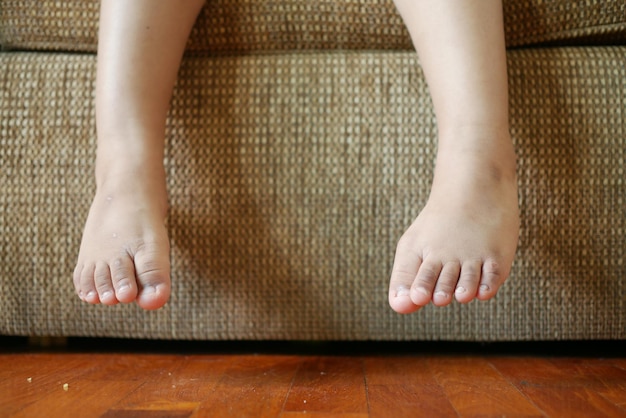 Close up of 5 years old child dry feet sitting on sofa