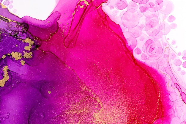 Close up abstract pink and purple gradient watercolor ink drops with gold streaks