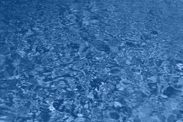 Close up abstract water texture. Swimming pool water in monochrome color background. Trendy blue and calm color. Copy space, top view.