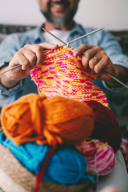 Photo close up of adult man working with ball yarn of colorful wool. happy people in indor hobbies activity using woolen and doing knitting work. indoor leisure activity