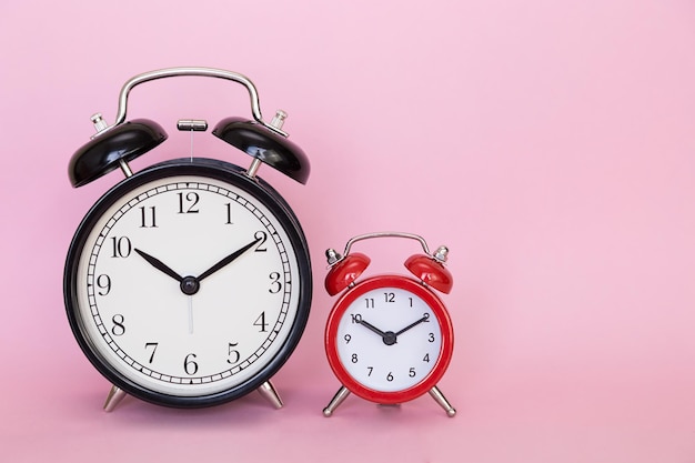 Close-up of alarm clocks against pink background