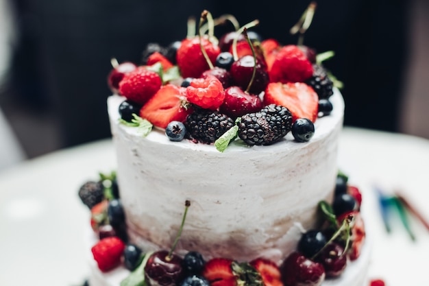 Close-up amazing fresh appetizing sweet cake with cream covered by refreshing fruit and berries