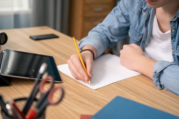 Close up american teenage boy writing notes study with laptop and books serious white man high schoo