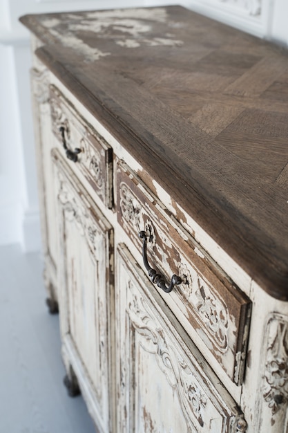 Close-up of ancient white commode bureau furniture with paint peeled off