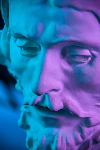 Close up antique portrait. Colorful gypsum copy of ancient statue of John the Baptist head for artists. Plaster sculpture man face. John baptized Jesus. Art poster in purple and blue bright colors.