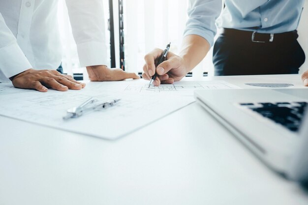 Close-up of architect discussing over blueprint at table in office