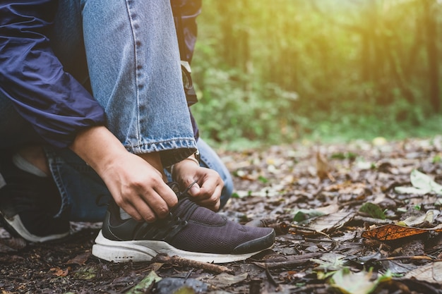 Close-up Asian woman tying shoelace at in rainforest.