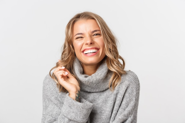 Close-up of attractive happy woman in grey sweater, laughing and smiling, express positivity