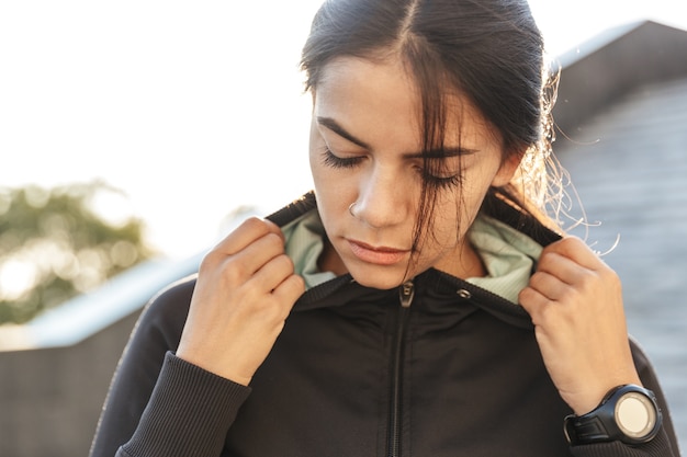 Close up of an attractive young fitness woman wearing sportswear exercising outdoors, posing