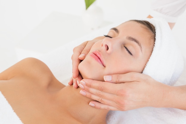 Close up of an attractive young woman receiving facial massage at spa center