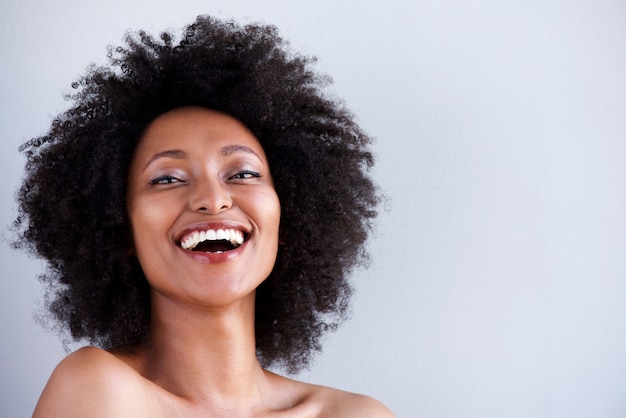 Close up attractive young woman with naked shoulders laughing on gray background