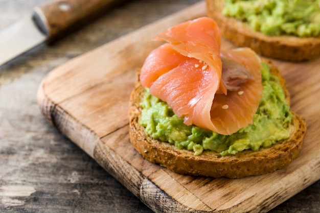 Close up avocado toast with fresh salmon on wooden table