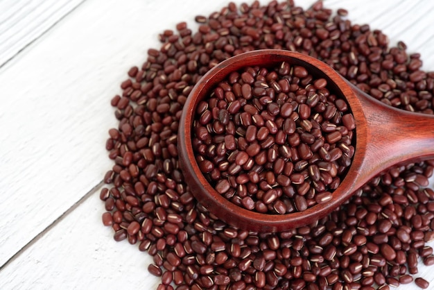 Close up of azuki beans in wooden scoop on white table background