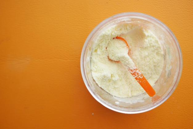 Close up of baby milk powder and spoon on tile background