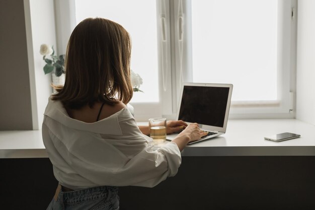 Close up of back view young pretty concentrated woman typing and browsing online on laptop working o