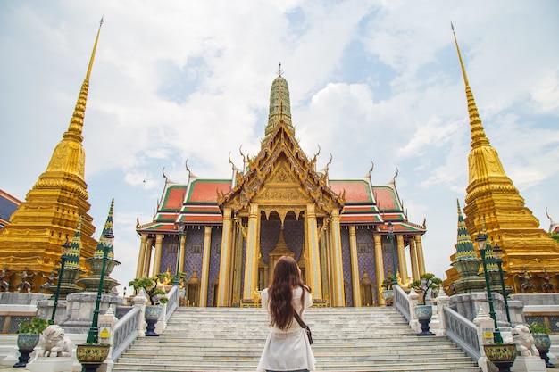 Close up backside portrait young Asian woman standing in front of The golden church inside Wat Phra Kaew, there is one of The most favorite temples in Bangkok Thailand.