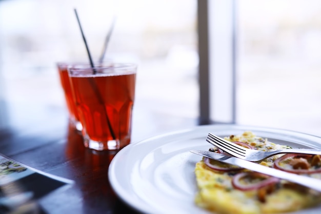 Close-up of bacon pizza, orange juice in a glass on the table in a cafe in a restaurant