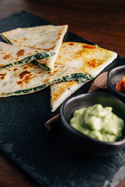 Close up Baked Spinach and Cheese Quesadillas served with Salsa and Guacamole.