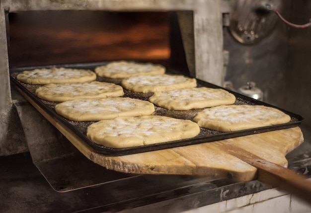 Close up of baker putting in the oven fresh pastry.