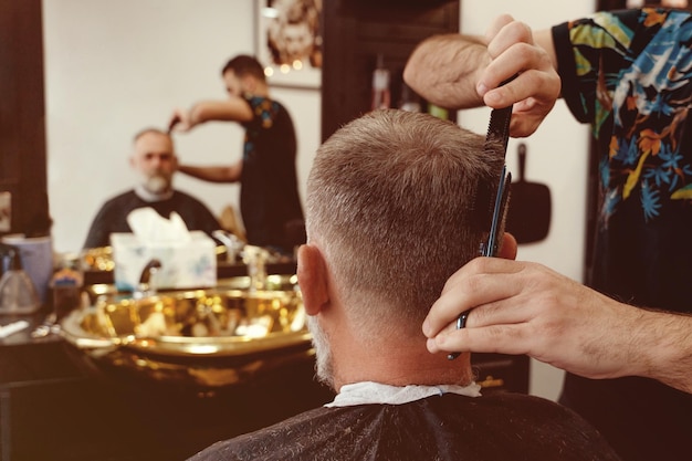 Close up barber trimming hair of old man