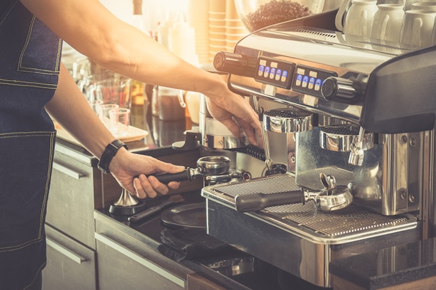 Close up, Barista making an espresso with a classic Italian coffee machine with steam and sunlight