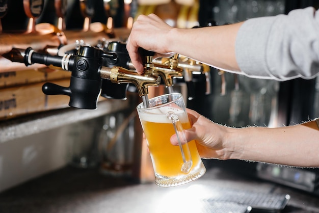 Photo close-up of the bartender filling a mug of light beer. the bar counter in the pub.