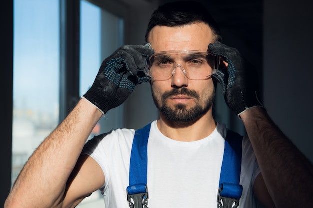 Close up, bearded construction worker wearing protective glasses