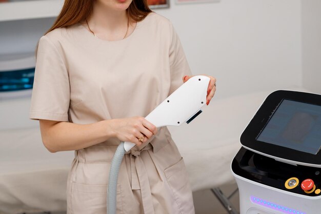 Close up of beautician hand in glove holding ultrasound device for face and skin lifting procedure and hair removal Young woman cosmetologist using modern cosmetology equipment in clinic