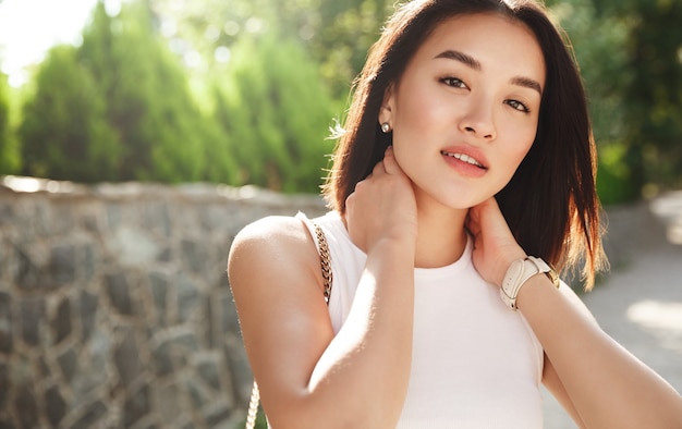 Close-up of beautiful asian woman standing in park and looking at camera with thoughtful face