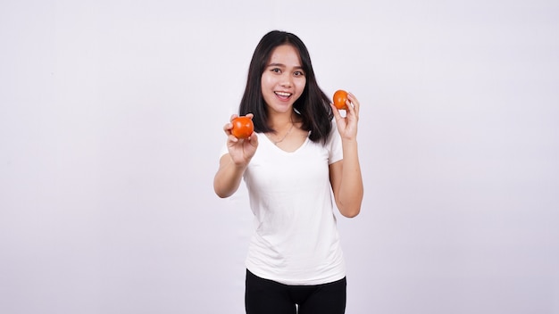 Close up beautiful asian women with a tomato isolated on white surface