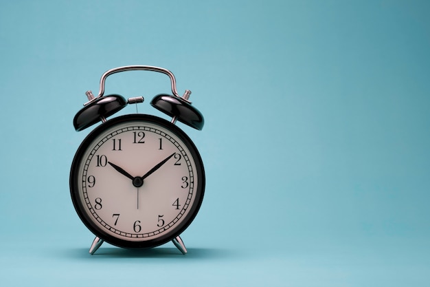 Close up of beautiful black alarm clock on green background