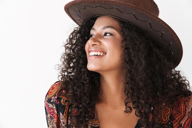 Close up of a beautiful cheerful young woman wearing cowboy hat standing isolated over white wall