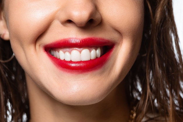 Close up of beautiful female smile with white teeth isolated on white studio background