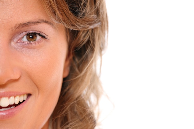 A close-up of a beautiful natural female face smiling over white background